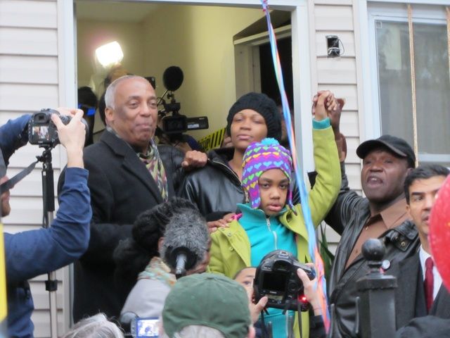 Alfredo Carrasquillo's daughter outside the house with her mother Tasha Glasgow and Council Member Charles Barron.